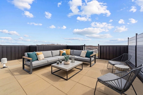 A patio with a grey sofa, a coffee table, and two chairs.