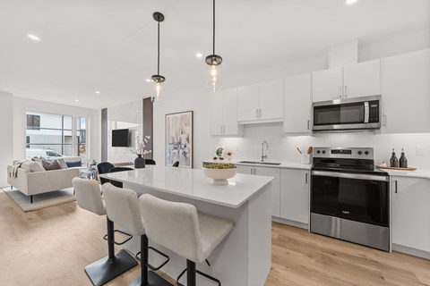 A modern kitchen with a white island and stainless steel appliances.