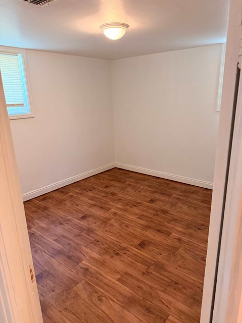 A room with wooden flooring and a window.