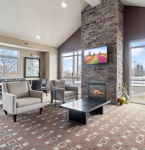 A living room with a stone fireplace and a television mounted above it.