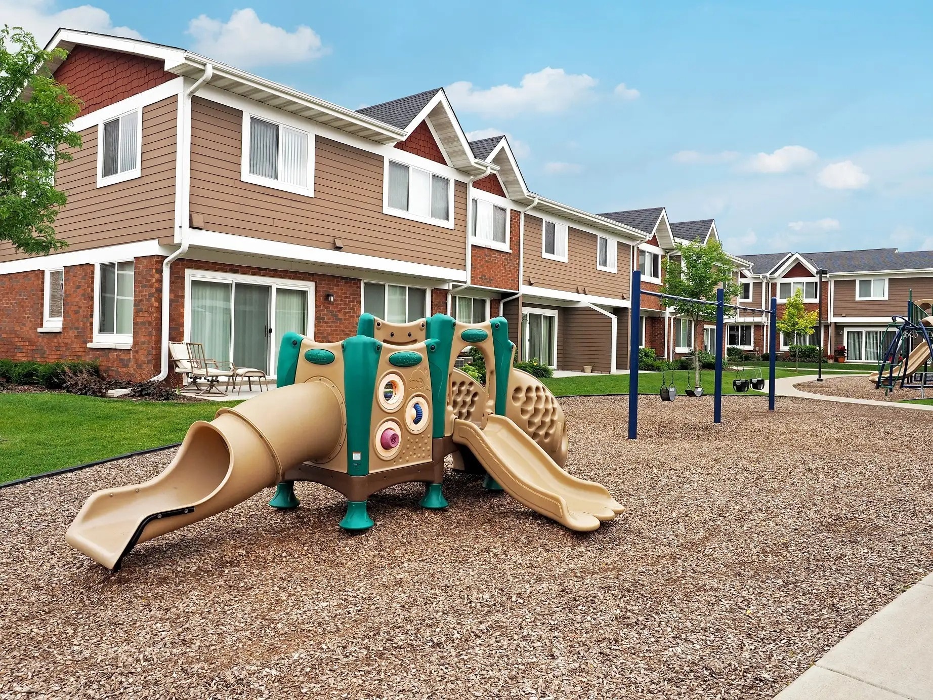A playground with a slide in front of apartment buildings.