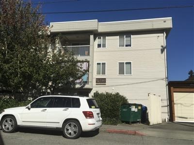A white SUV is parked in front of a two-story apartment building.