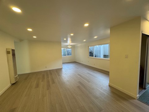 A spacious room with wooden flooring and recessed lighting.