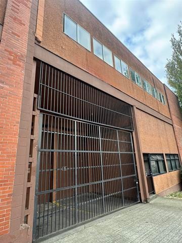 A large metal gate is closed on a brick building.