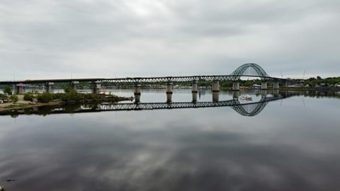 A bridge spans across a body of water under a cloudy sky.