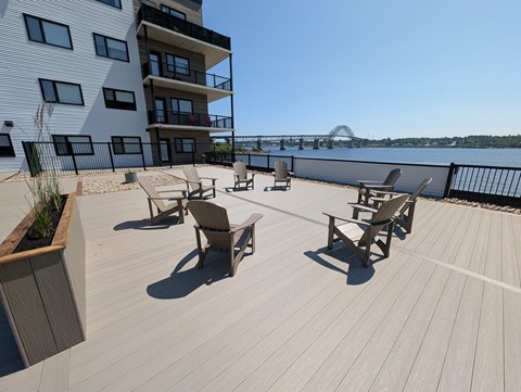 A wooden deck with chairs and a building in the background.
