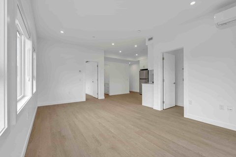 A spacious room with wooden flooring and white walls.