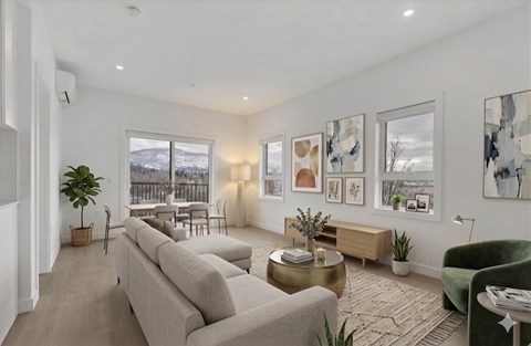 A living room with a grey sofa, a green armchair, a coffee table, and pictures on the wall.