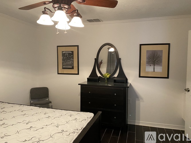 A bedroom with a bed, dresser, mirror, and two pictures on the wall.