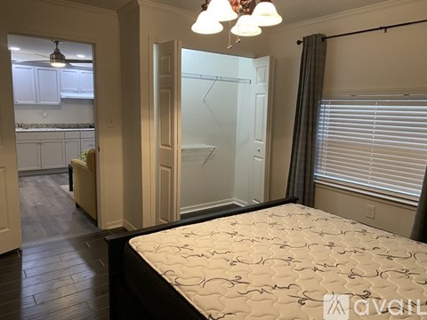 A bedroom with a bed, a window with blinds, and a closet with a glass door.