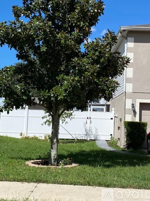 A tree in a grassy area in front of a building.