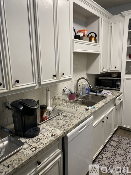 A kitchen with white cabinets and granite countertops.