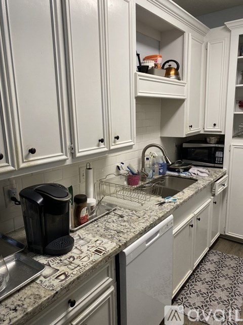 A kitchen with white cabinets and granite countertops.