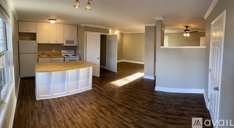 A kitchen with a wooden floor and white walls.