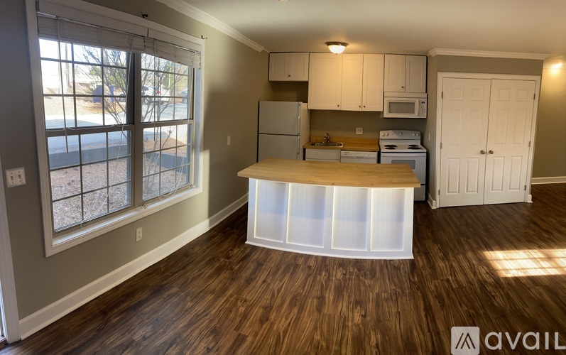 A kitchen with a wooden floor and white cabinets.