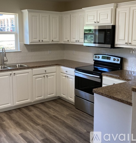 A kitchen with white cabinets and a black stove top oven.