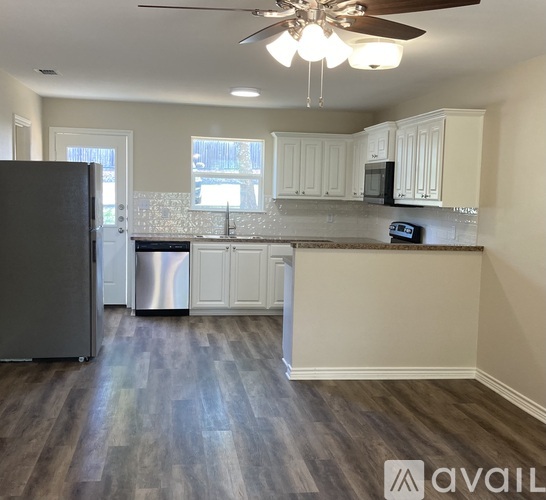 A kitchen with a black fridge and wooden floors.