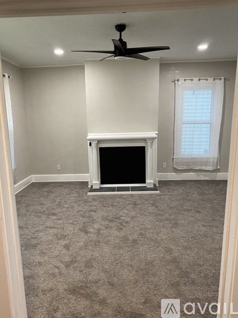 A living room with a fireplace and a ceiling fan.