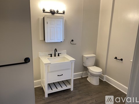 A white bathroom with a sink, toilet and a mirror.