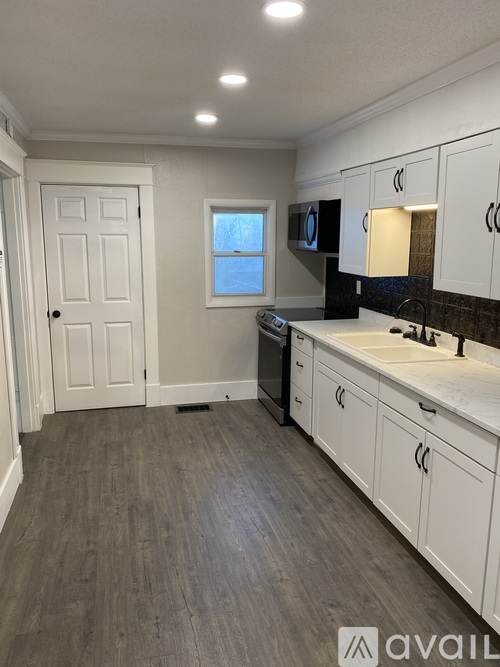 A kitchen with white cabinets and a grey floor.