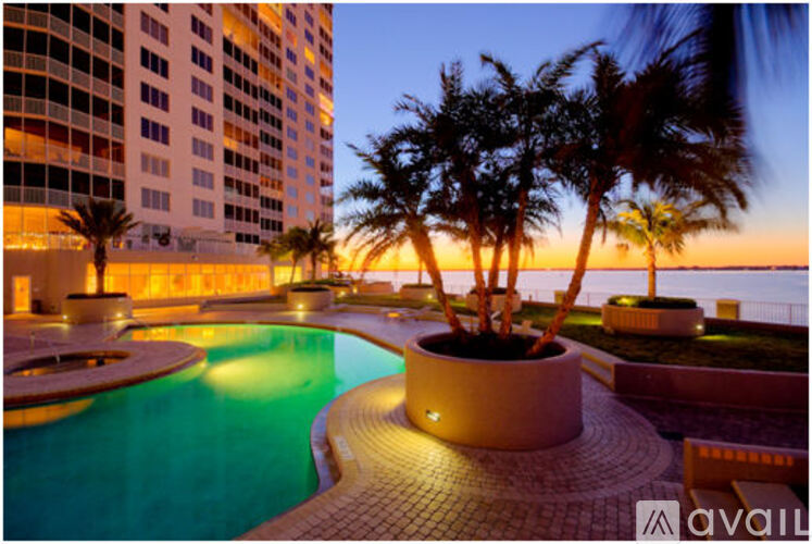 A pool surrounded by palm trees at sunset.