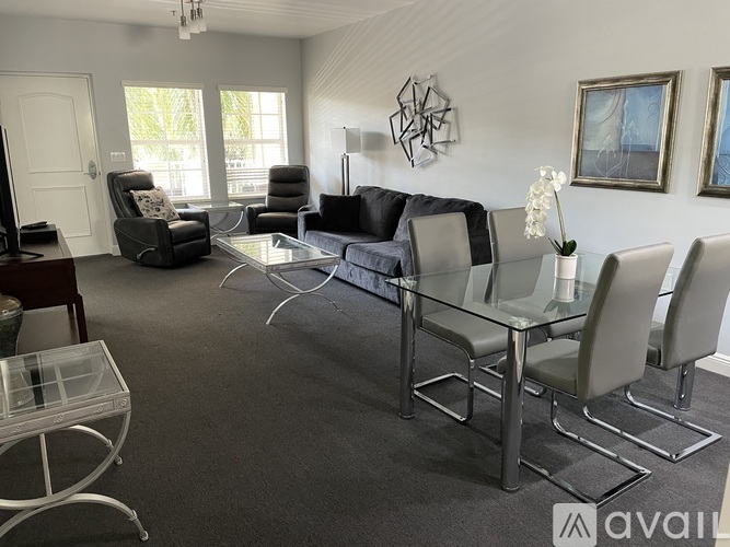 A living room with grey and black furniture and a glass table.