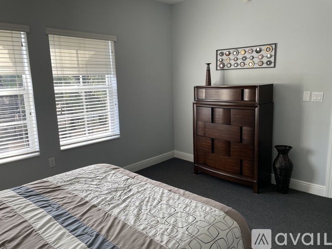 A bedroom with a bed, a wooden dresser, and a vase on the floor.