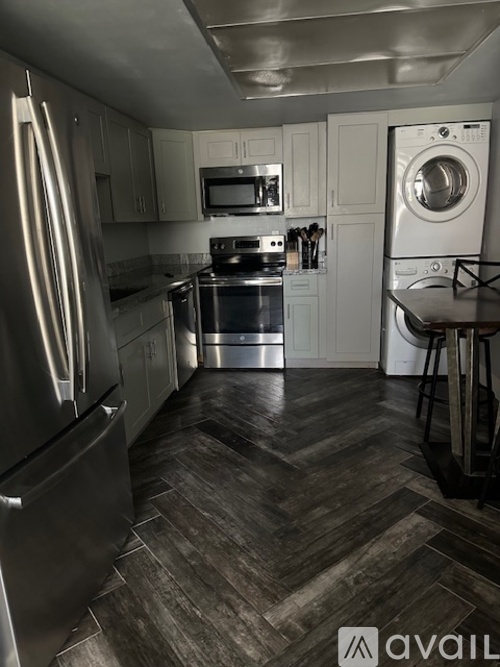A kitchen with a refrigerator, microwave, oven, and washing machine.
