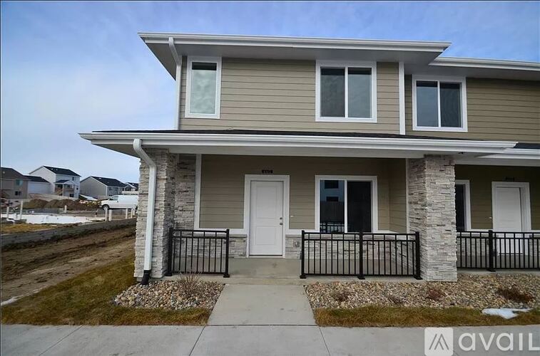 A house with a grey siding and a white door is for sale.