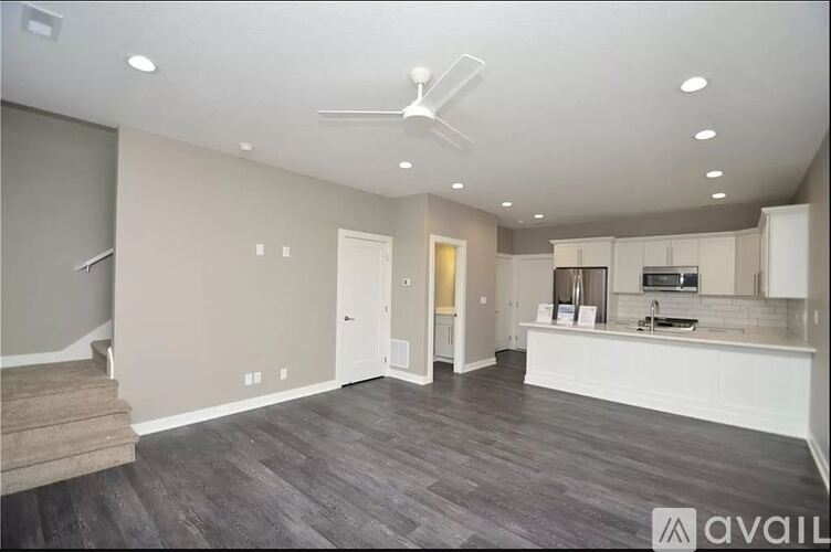 A spacious living room with a staircase on the left and a kitchen area on the right.