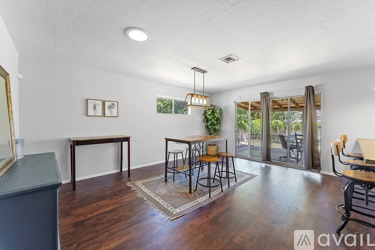 A room with wooden floors and a large window with a view of trees.