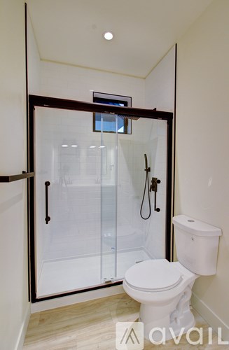 A white toilet sits in a bathroom with a walk-in shower.