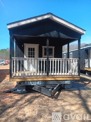 A small house with a porch is being transported on a trailer.