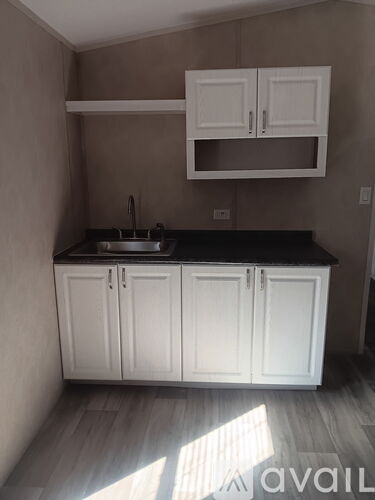 A kitchen with white cabinets and a black countertop.