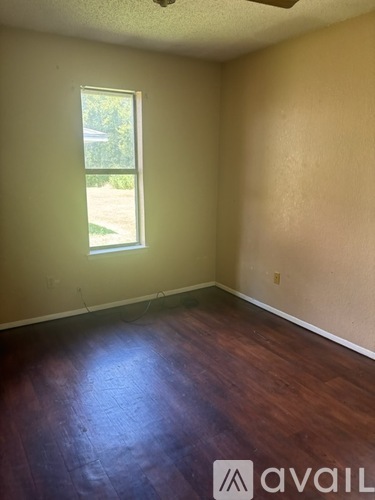 A room with a window and wooden flooring.