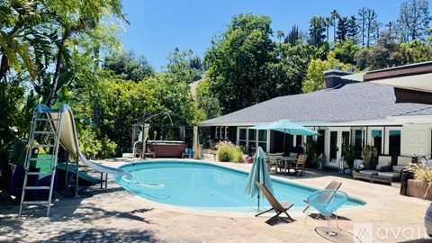 A pool with a slide and a sun lounger.