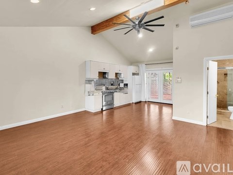 A spacious room with wooden flooring and a ceiling fan.