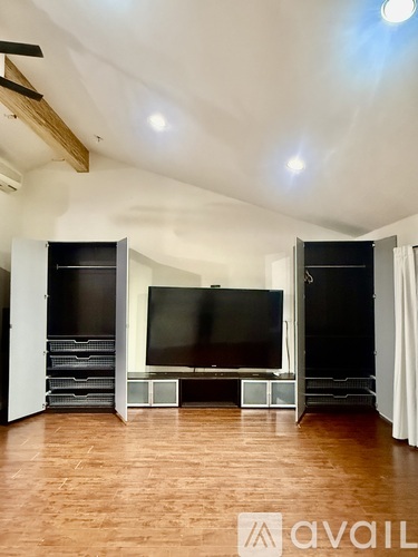 A living room with a television and a wooden floor.