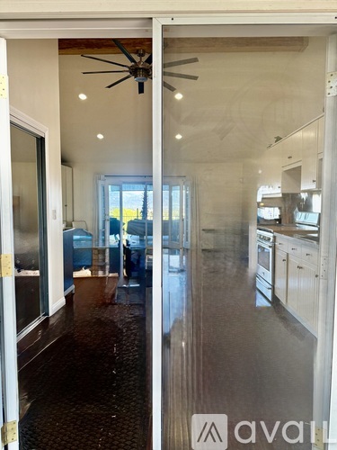 A modern kitchen with a fan on the ceiling and a dining area with a table and chairs.