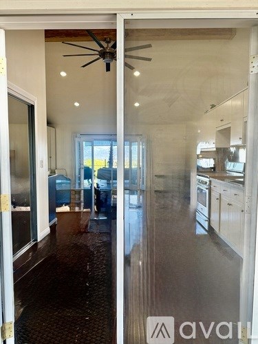 A modern kitchen with a fan on the ceiling and a dining area with a table and chairs.