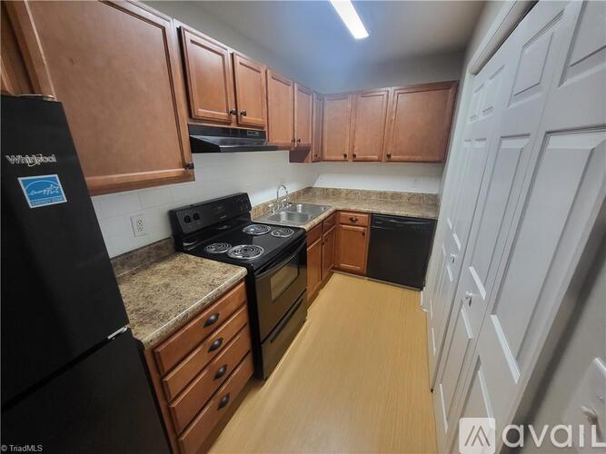 A kitchen with wooden cabinets and a black refrigerator.