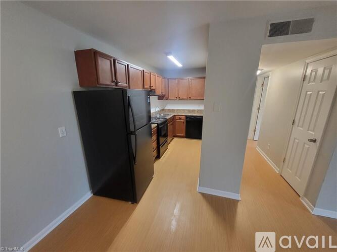 A kitchen with a black refrigerator and wooden cabinets.