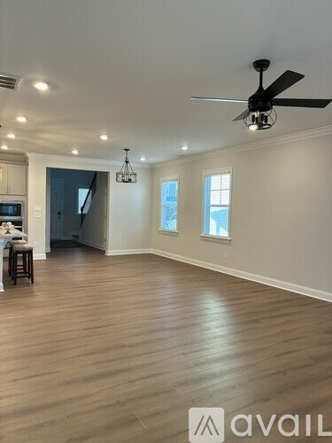 A spacious room with a ceiling fan and hardwood flooring.