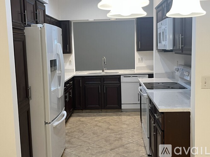 A kitchen with black cabinets and a white refrigerator.