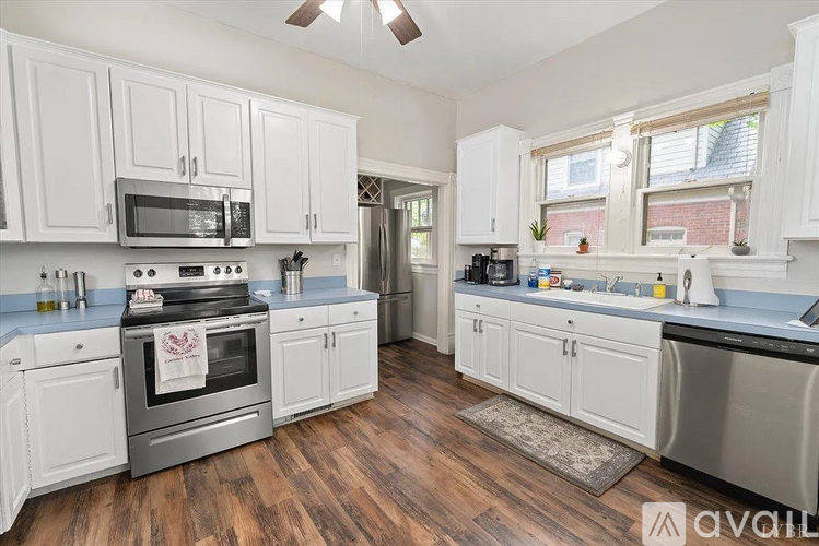 A kitchen with white cabinets and a wooden floor.