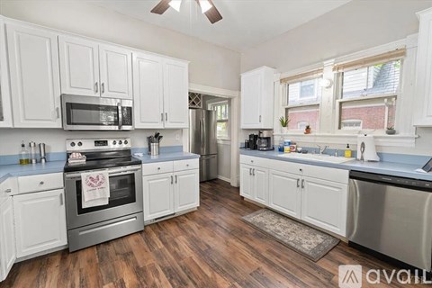 A kitchen with white cabinets and a wooden floor.