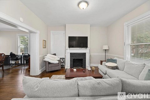 A living room with a grey couch and a fireplace.