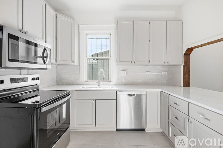 A kitchen with white cabinets and black appliances.