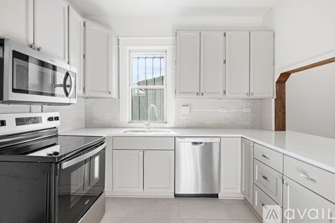A kitchen with white cabinets and black appliances.