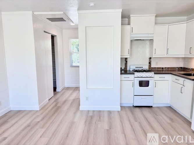 A kitchen with white cabinets and a stove top oven.
